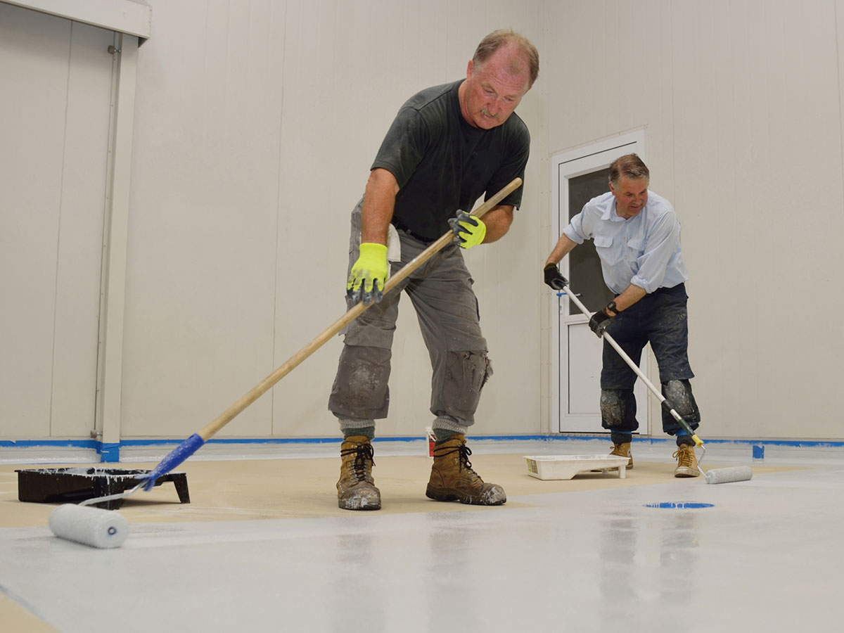Image of two men applying an epoxy coating onto a garage floor